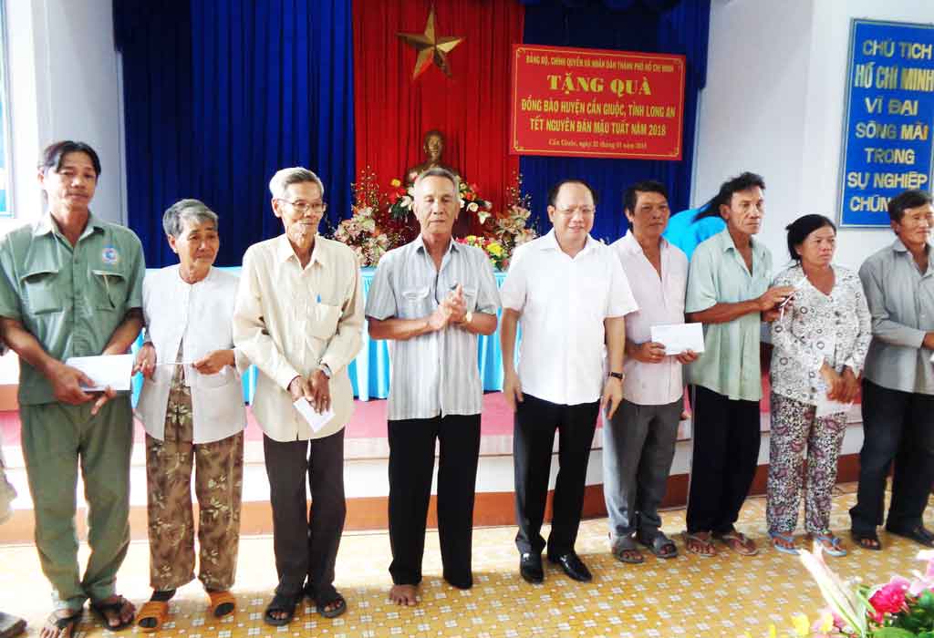 Deputy Standing Secretary of HCMC Party Committee Tat Thanh Cang (fifth from left) gives Tet gifts to disadvantaged families in Can Giuoc District