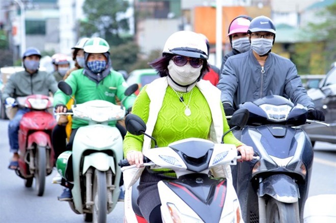 Residents in Hanoi wear masks while driving to protect themselves from air pollution.(Source: VNA)