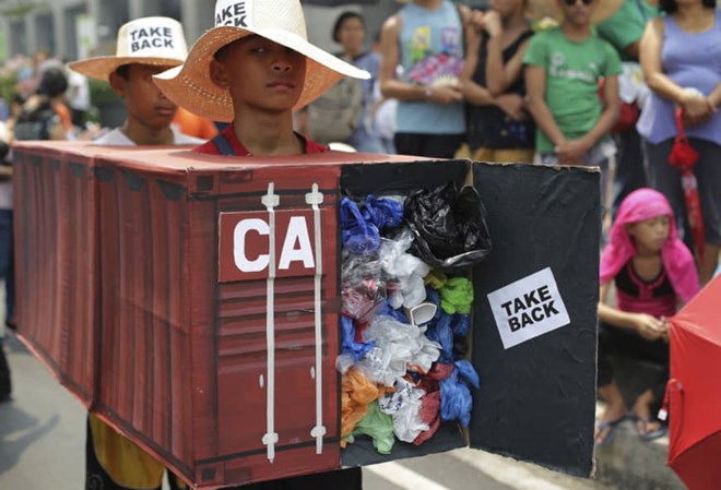 Filipino environmental activists wear a mock container vans filled with garbage to symbolize the 50 containers of waste that were shipped from Canada to the Philippines two years ago as they hold a protest outside the Canadian Embassy in the financial district of Makati, south of Manila, on May 7. (Source: AP)