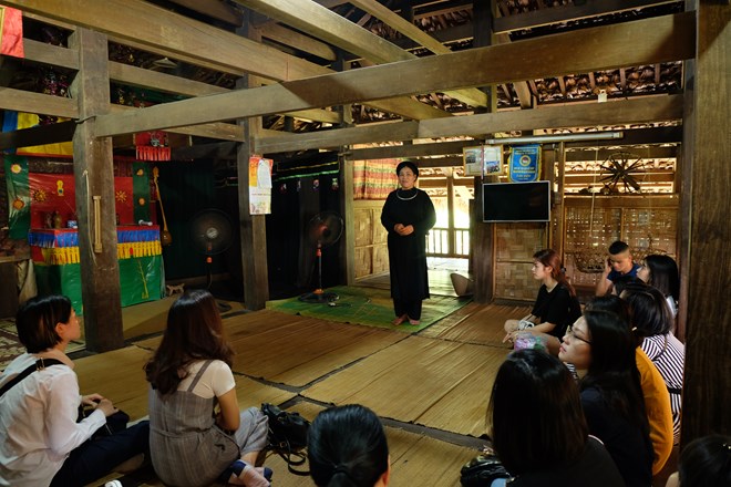 Nguyen Thi Xuyen, a Tay woman from Thai Nguyen province, introduces the traditional house of her community to visitors (Photo: VNA)