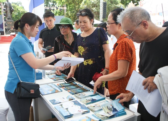 Visitors seek information at the Vietnam Airlines booth at the tourism festival that opened in Hanoi on July 6 (Photo: VNA)