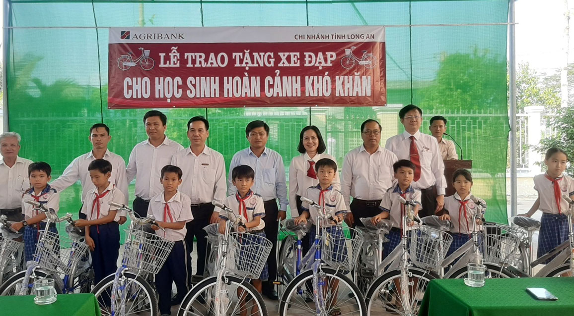 Phạm Quốc Bảo (hàng đầu, thứ 4, trái qua) nhận xe đạp do Agribank Chi nhánh Long An tài trợ