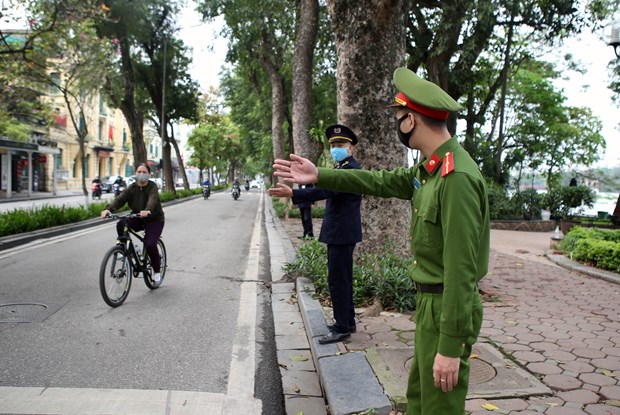 Officers remind a cyclist near Hoan Kiem Lake in Hanoi about social distancing (Photo: VNA)