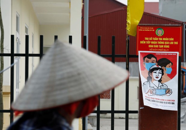 A farmer rides a bicycle past a poster warning about the coronavirus disease outbreak in Hanoi on April 22 (Photo: Reuters)