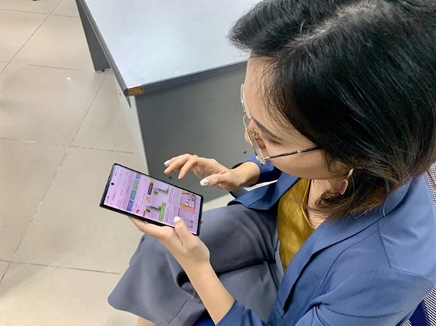 A woman browses an e-commerce website on her phone (Photo: VNA)