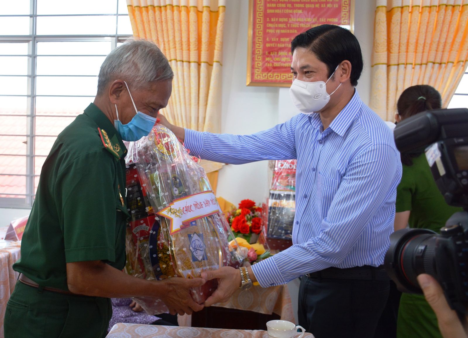 Hero of the People's Armed Forces Tran Van Nam receives the Tet gift from the Secretary of Can Giuoc district's Committee - Pham Van Bon