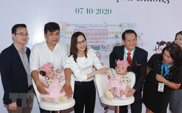 The twins, Truc Nhi and Dieu Nhi, their parents and medical workers pose for a photo on the day they are discharged from hospital (Photo: VNA)