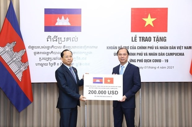 Vietnamese Deputy Minister of Foreign Affairs Nguyen Quoc Dung (R) presents the token of the aid worth 200,000 USD to Cambodian Ambassador to Vietnam Chay Navuth. (Photo: VNA)