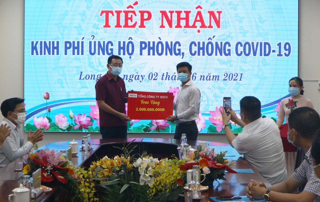 Representative of IDICO Corporation (R) presents a symbolic board to support 2 billion VND