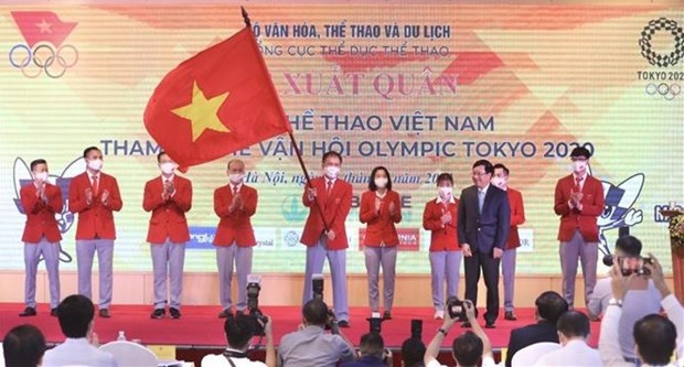 A member of the Vietnamese sports delegation holds the national flag handed over by Deputy Prime Minister Pham Binh Minh (front, right) at the send-off ceremony on July 13 (Photo: VNA)