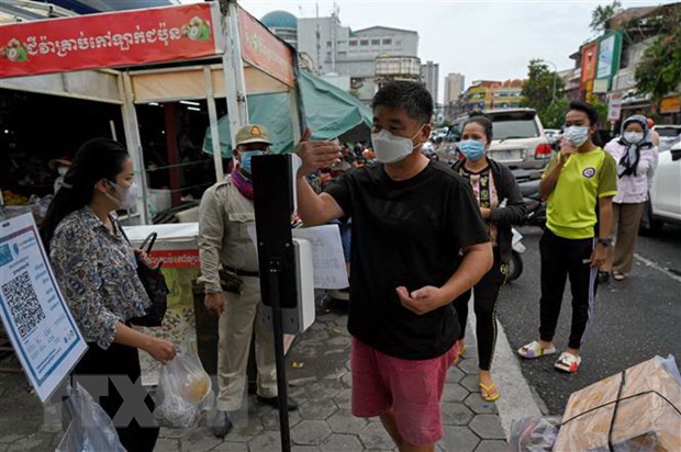 Kiểm tra thân nhiệt phòng lây nhiễm COVID-19 trước khi vào chợ tại Phnom Penh, Campuchia. (Ảnh: AFP/TTXVN)