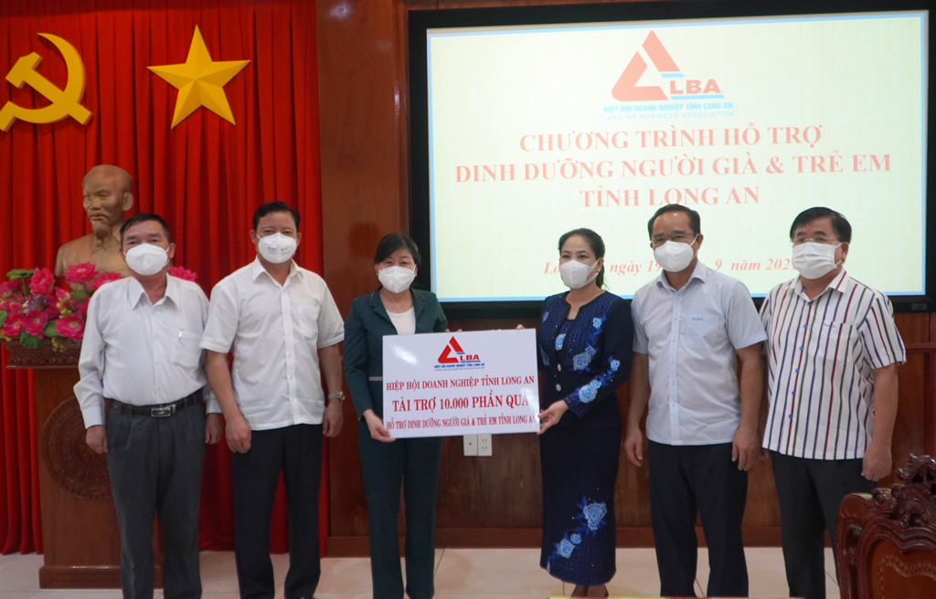 Standing Vice Chairwomam of the Provincial Business Association - Ninh Thi Bich Thuy (3rd, R) presents a symbolic board to support 10,000 gifts to Long An province