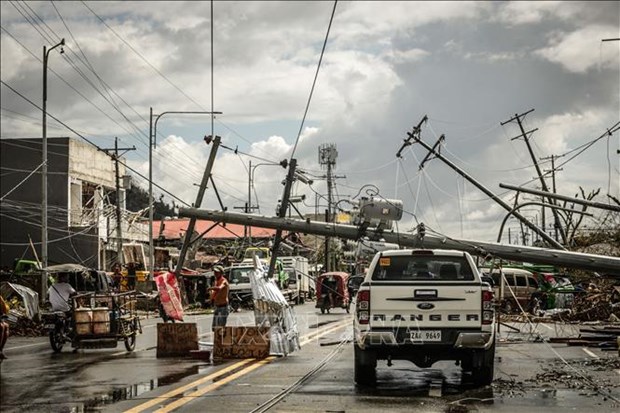 Fallen electric pylons block a road while a sign asking for food (L), is displayed along a road in Surigao City, the Philippines. (Photo: AFP/VNA)