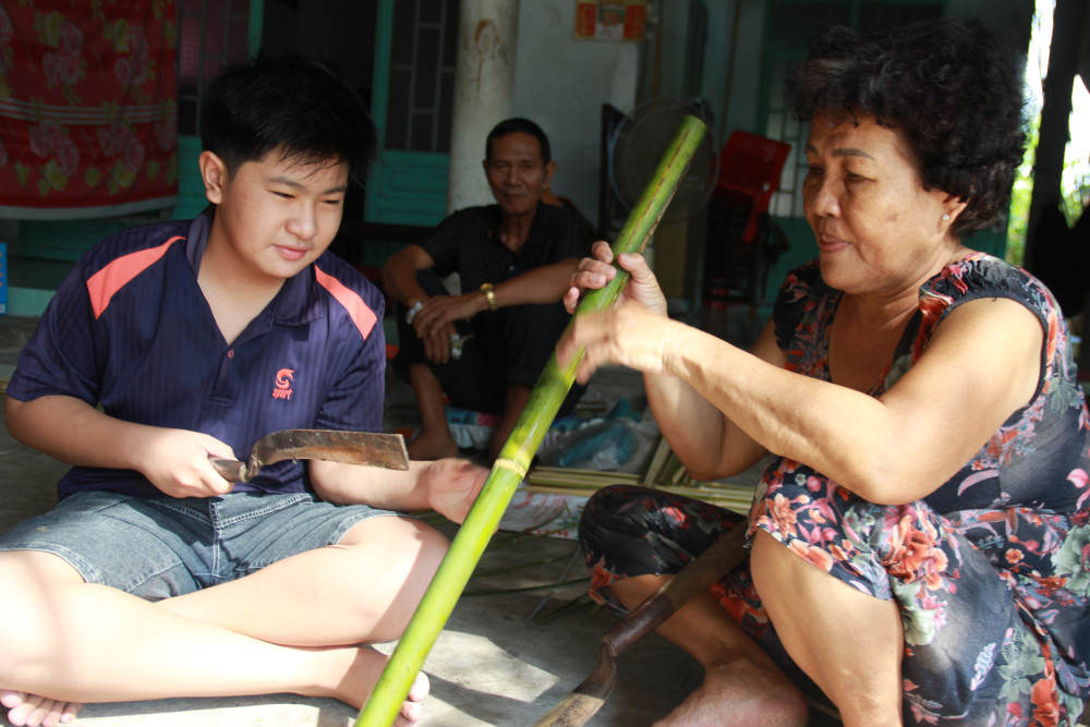 Cô Phạm Thị Rí (ấp Bến Long, xã Tân Mỹ, huyện Đức Hòa) đang truyền nghề cho cháu nội